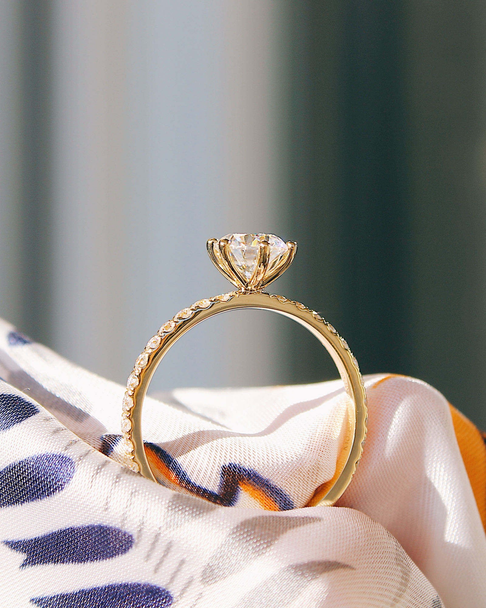 Delia - 18K Gold Verlobungsring mit Round Brillinat Cut und pavébesetzter RIngschiene, Seitenansicht mit Fassung