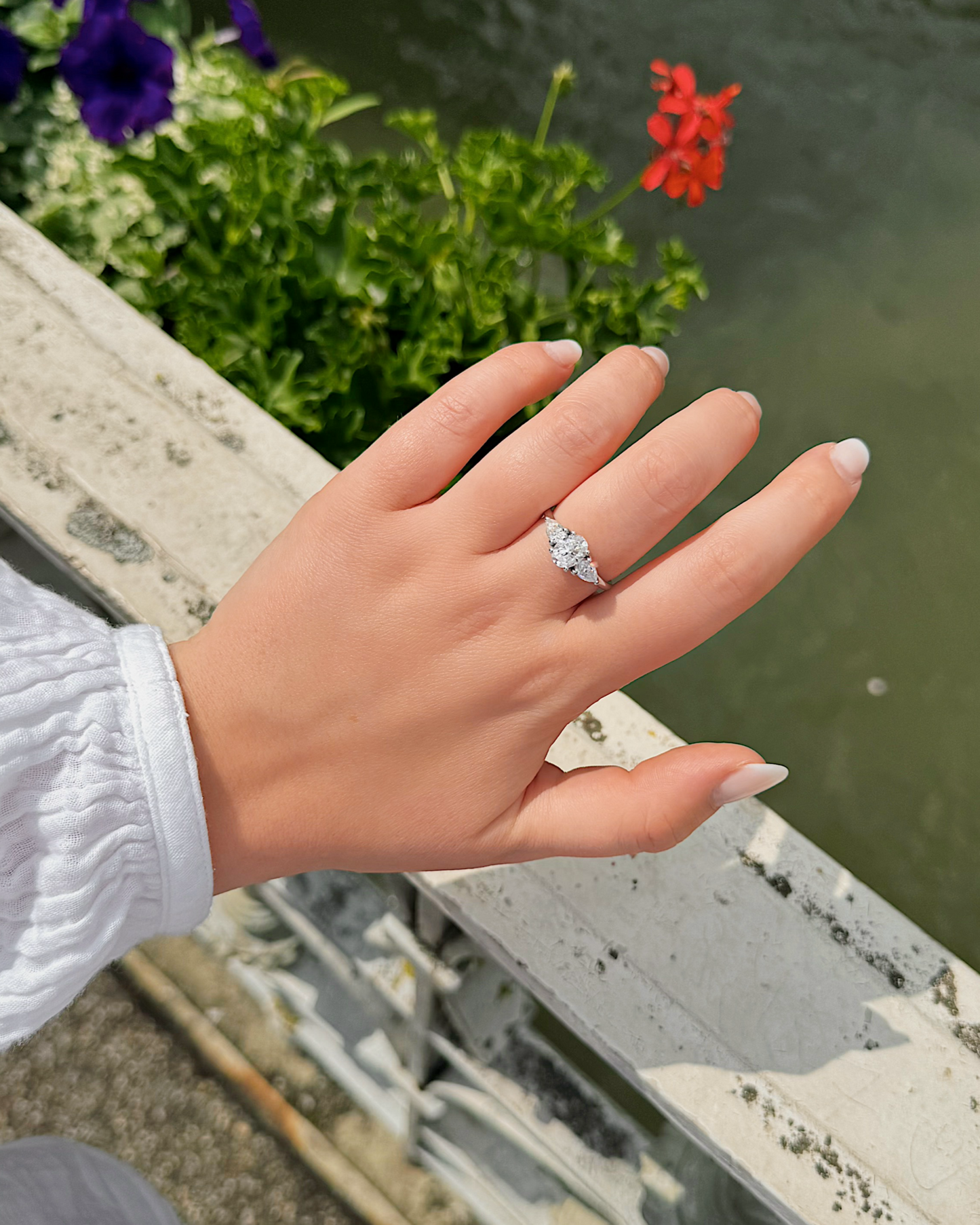 Nola - 18K Gold Trilogy Ring mit Oval Cut Mittelstein und zwei pear Cut Seitensteinen, getragen an der Hand, Frontansicht