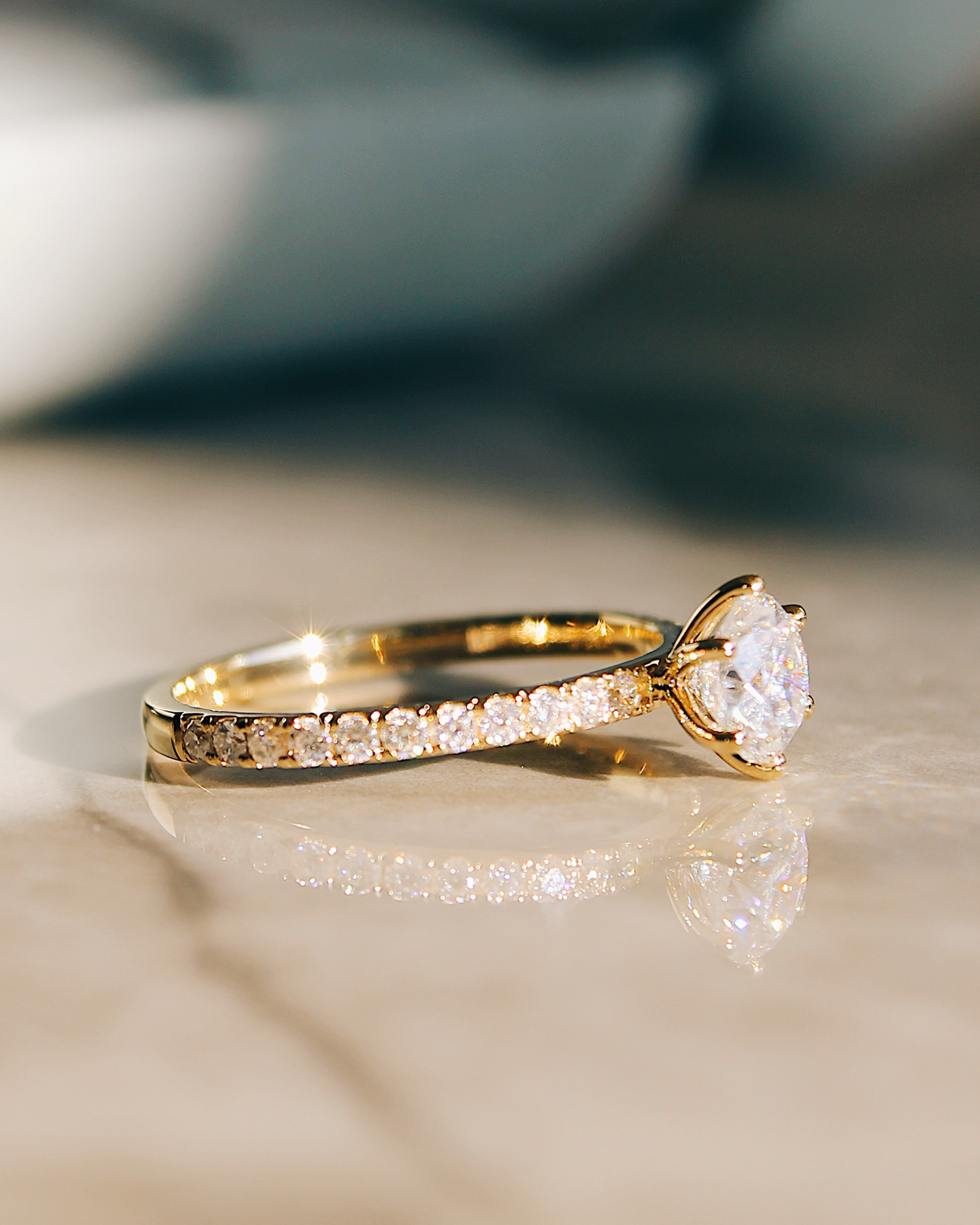 Delia - 18K Gold Verlobungsring mit Round Brillinat Cut und pavébesetzter RIngschiene, Seitenansicht liegend