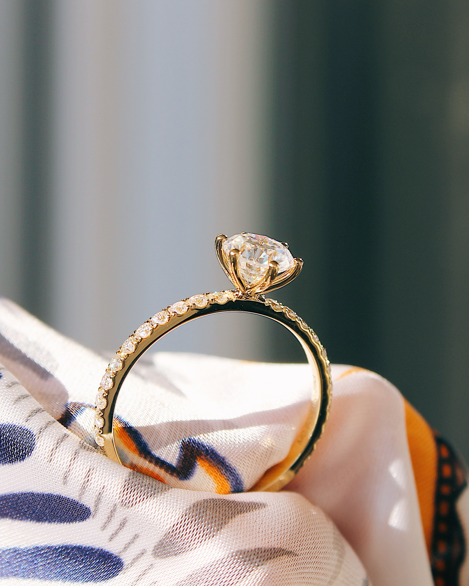 Delia - 18K Gold Verlobungsring mit Round Brillinat Cut und pavébesetzter RIngschiene, Seitenansicht