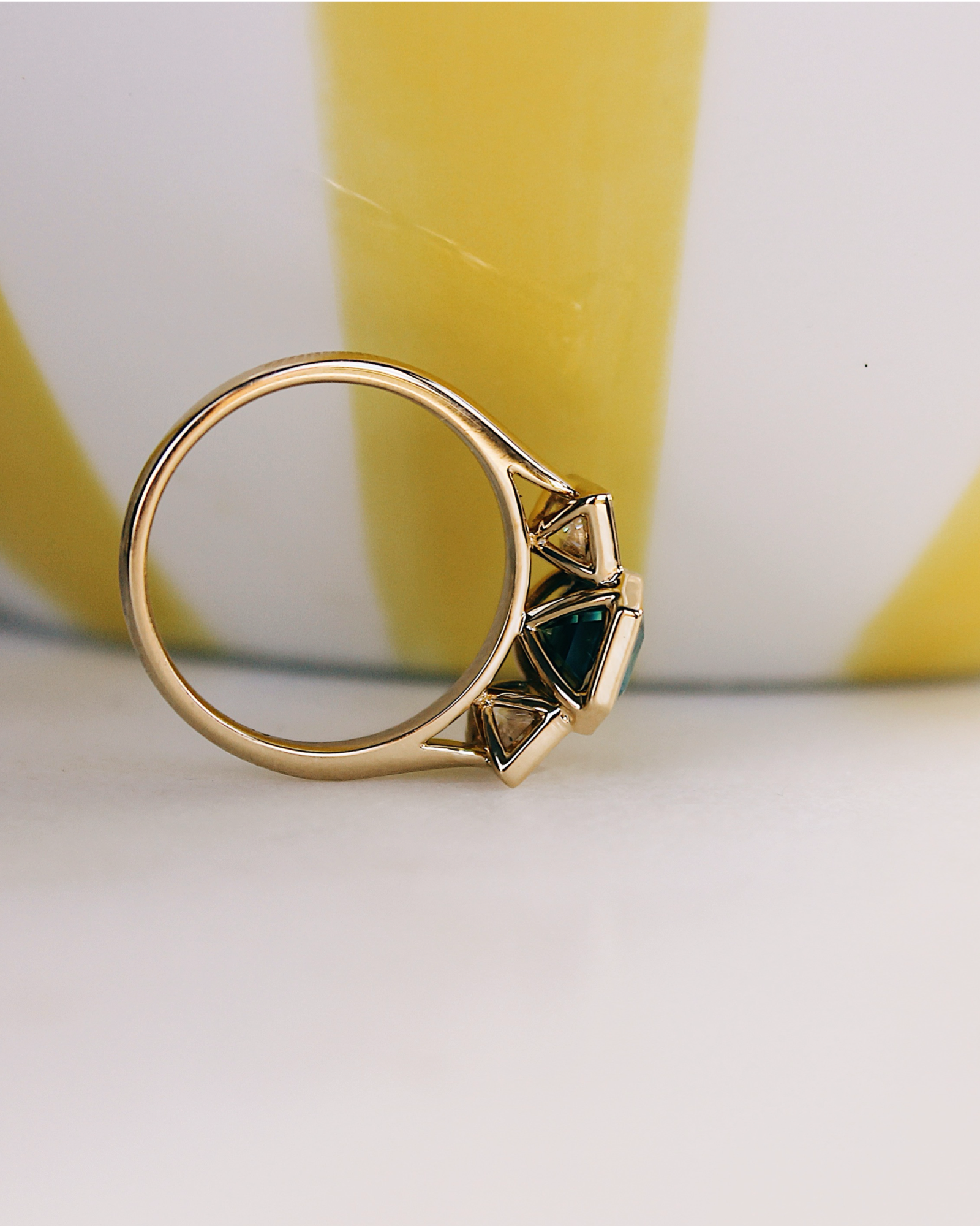 18K Trilogie Goldring Olivia mit einem grünen Emerald Cut Moissaniten und zwei Baguette Seitensteinen, Details der Fassung